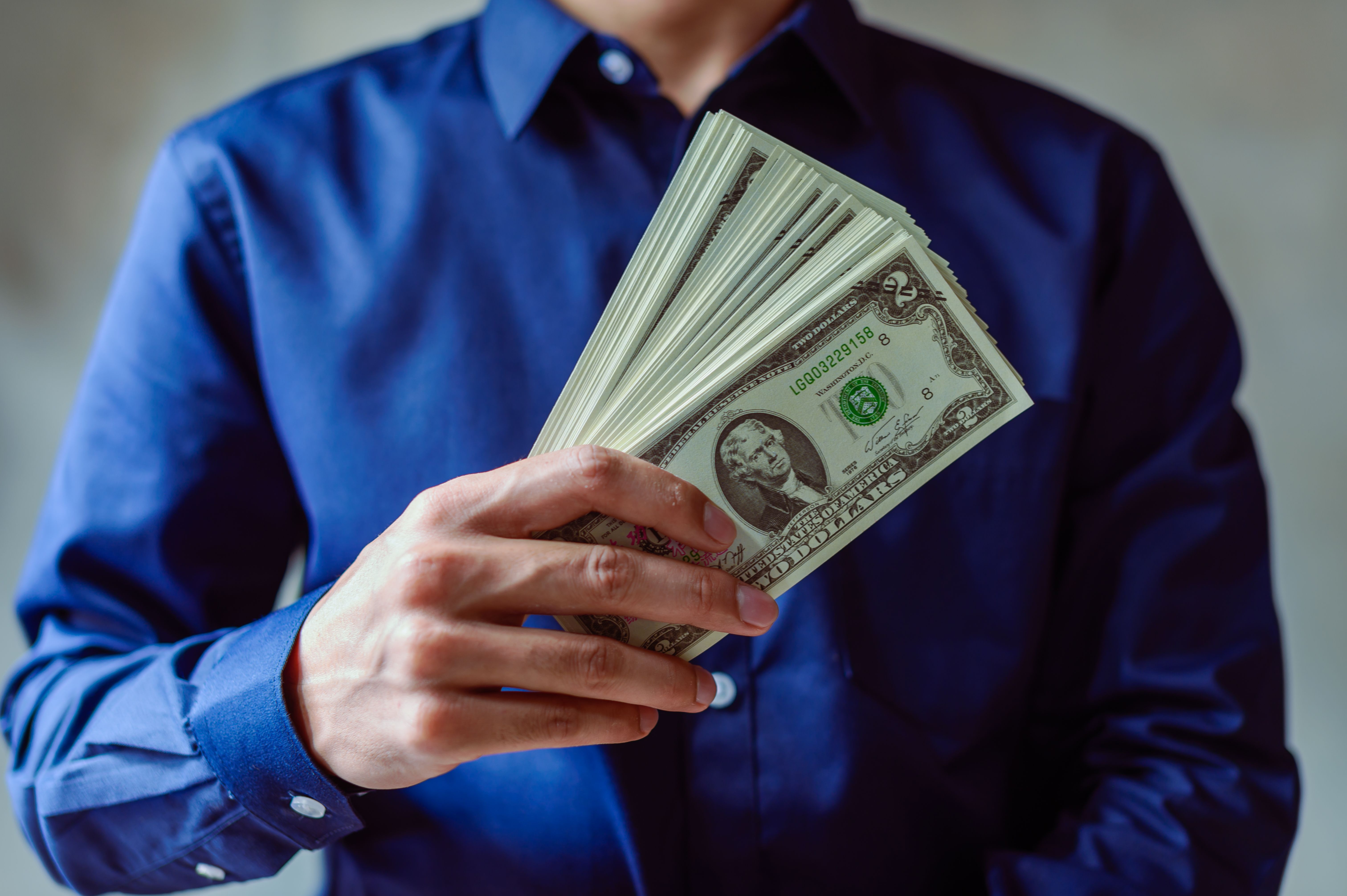 Hands fanning out a stack of cash, for extra cash from the affiliate program